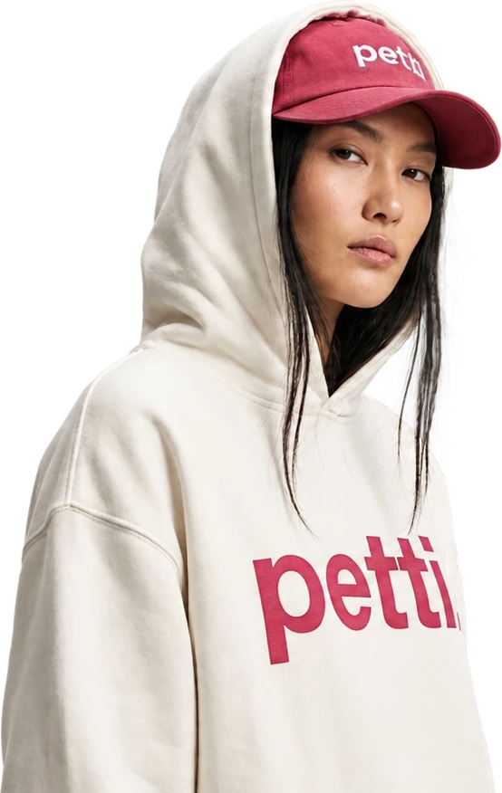 Someone wearing the cream Petti hoodie and the rose Petti cap